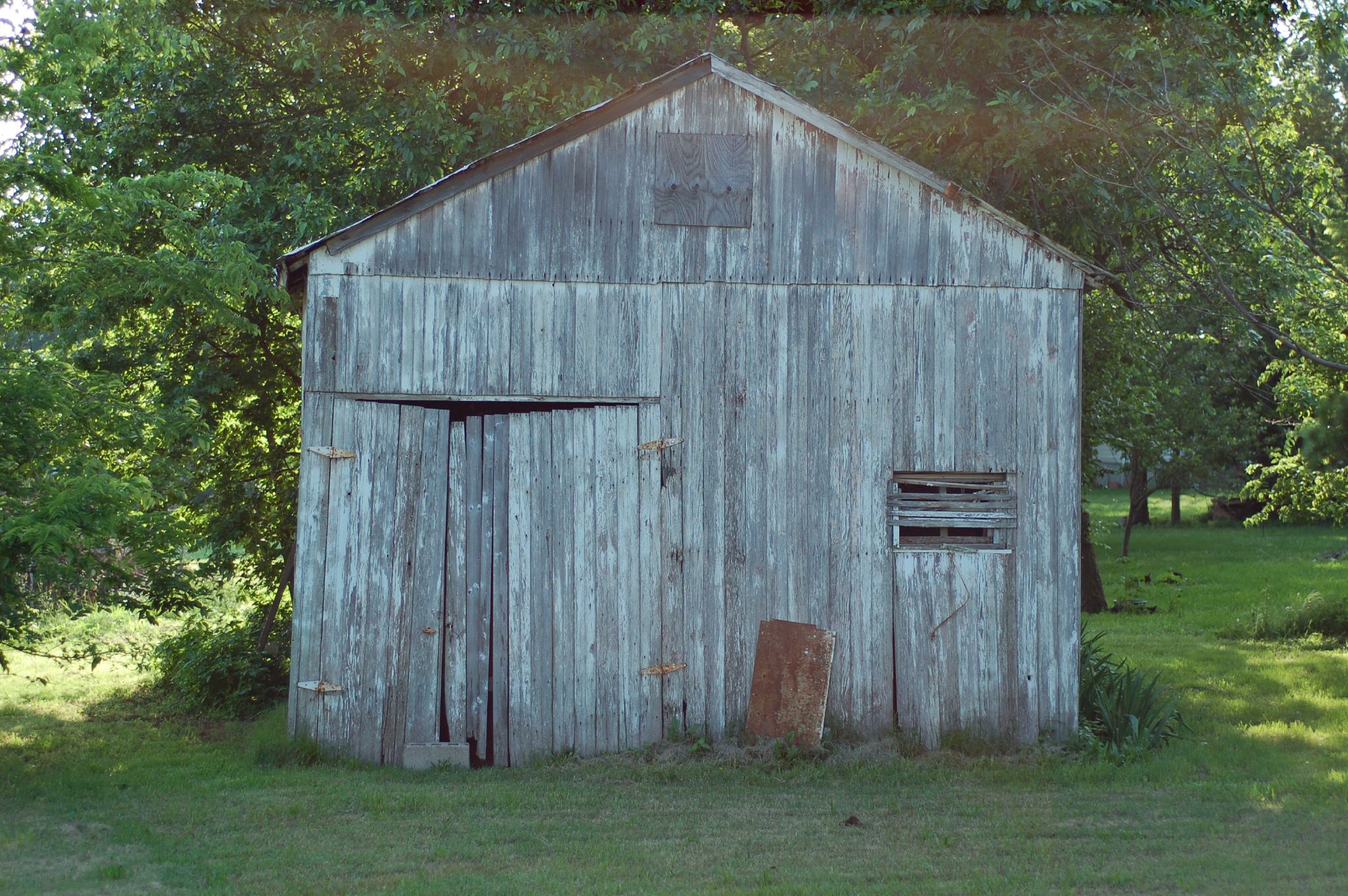 an old shed with doors and windows is sitting in a field