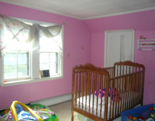 a pink room with crib, toy chest, and toys