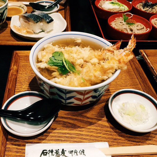 a bowl of noodles and shrimp on a wooden tray