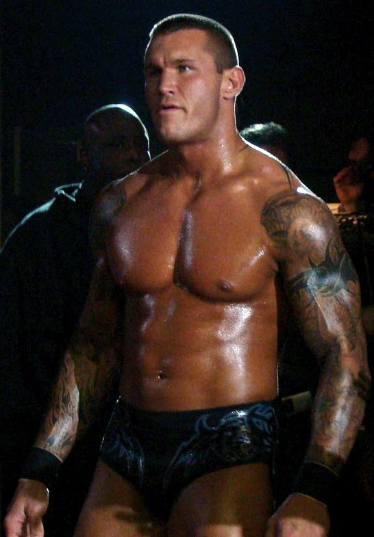 a male wrestler posing for a picture in a dark room