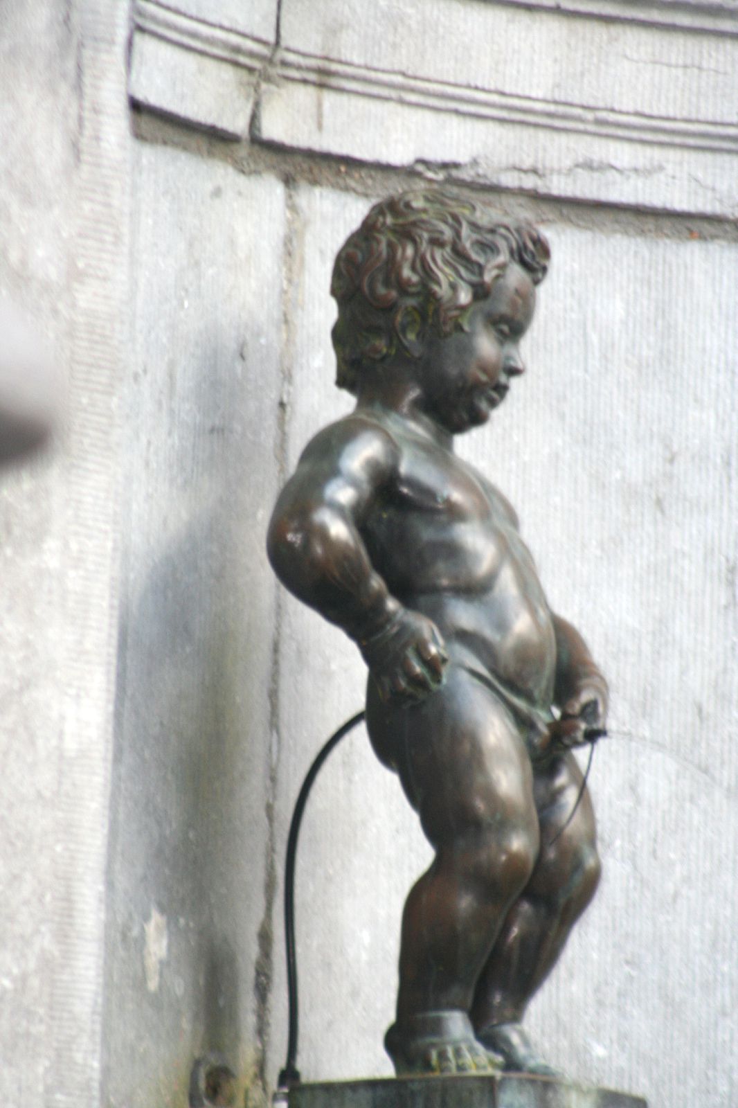 bronze statue of little boy holding an electric water hose