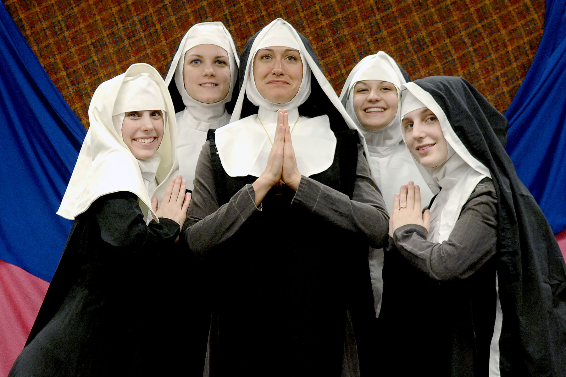 nun girls in white and black with folded hands, posing for the camera