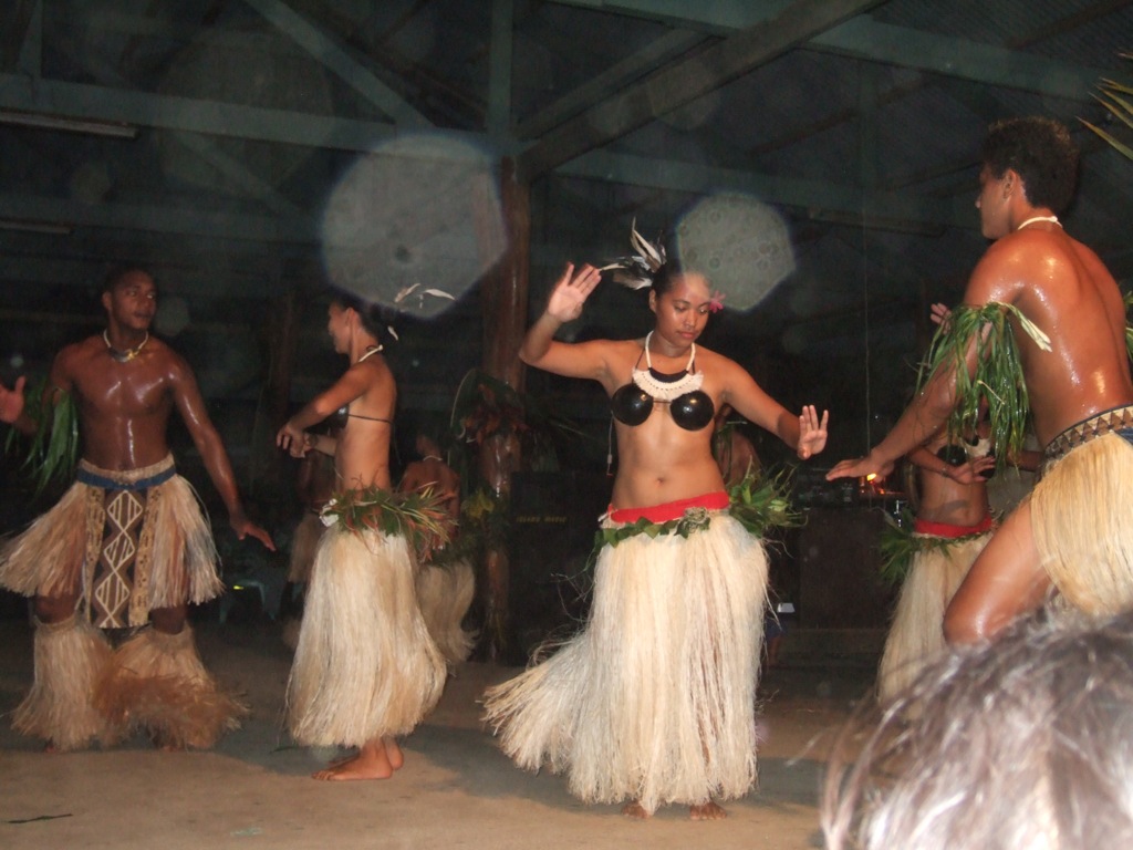 some people wearing hula skirts dancing in an open area