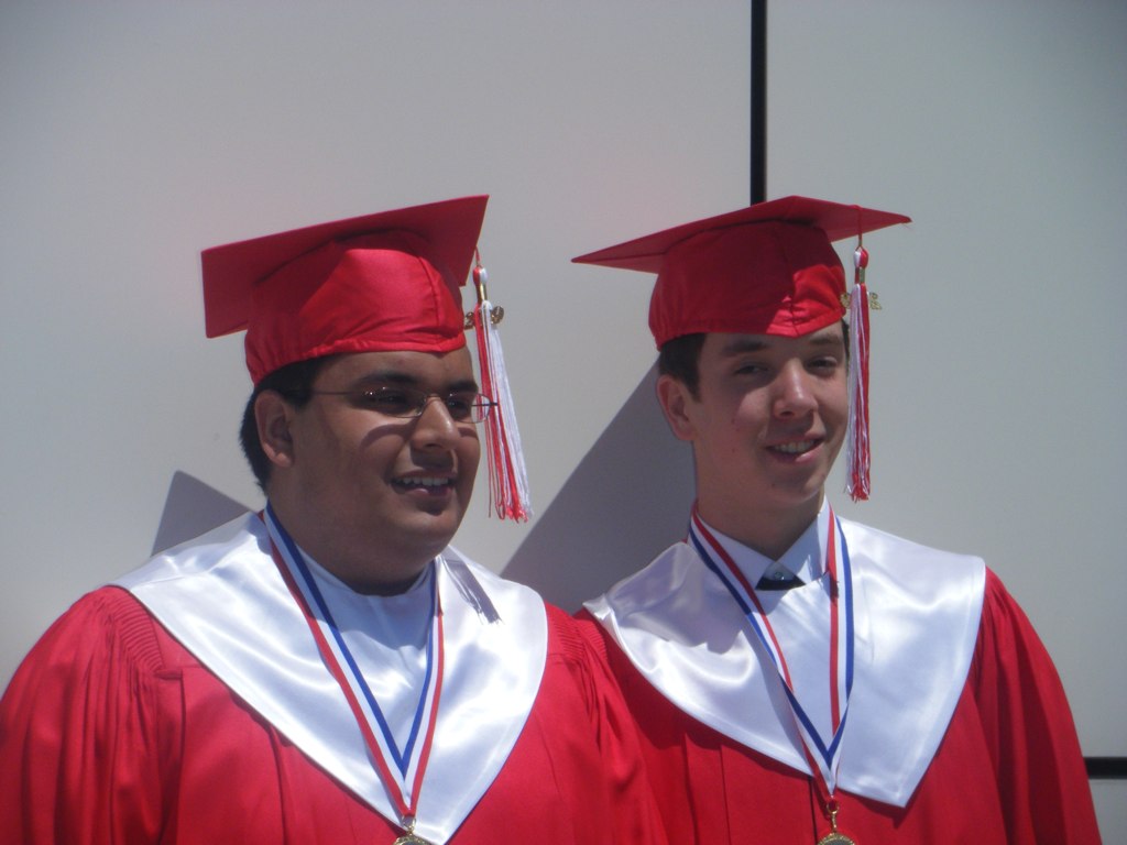 two men standing next to each other wearing graduation attire