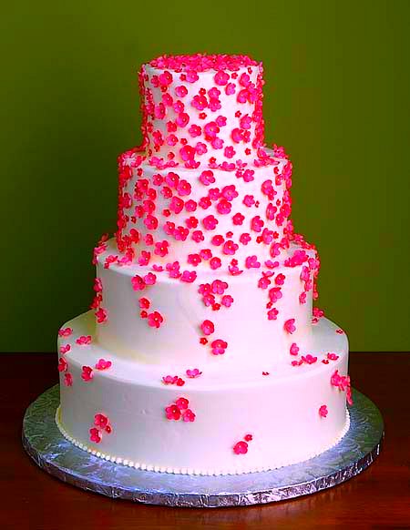 a white three tier cake with a pink flower arrangement
