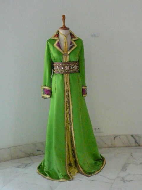 a green dress on a mannequin with jewels and belt
