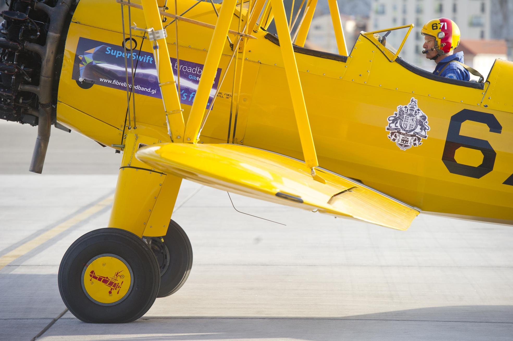 a small yellow biplane parked on the tarmac