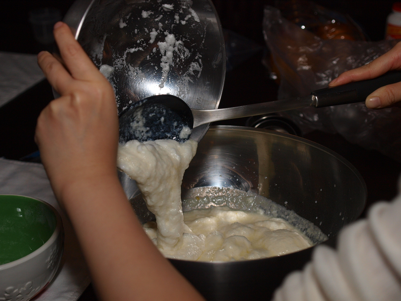 two hands pour batter into a mixing bowl
