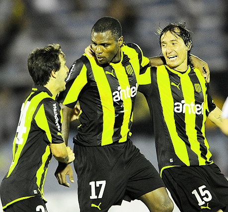 three soccer players in black and yellow uniforms celete