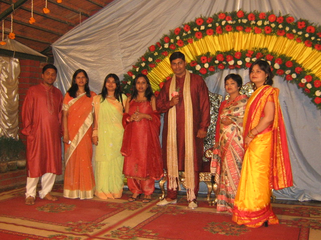 a group of people posing in front of a stage decorated with flowers and garlands