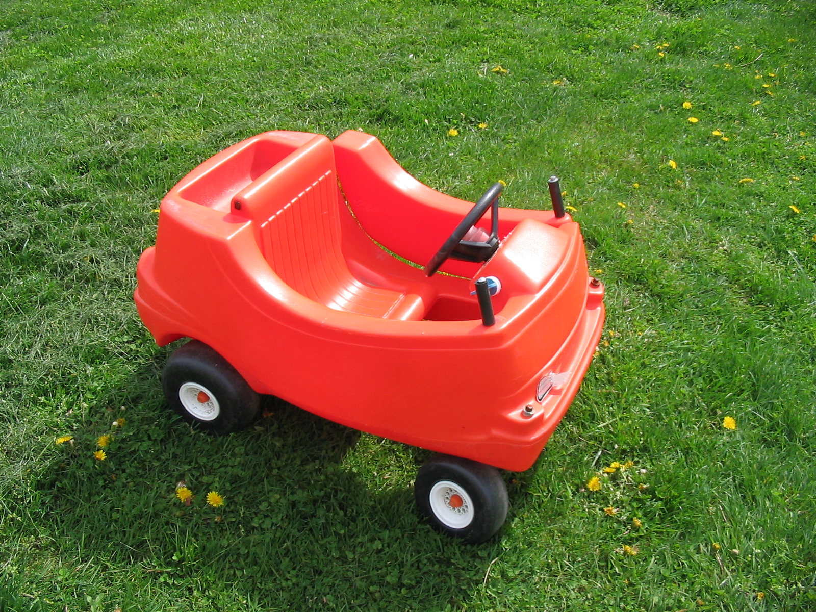 a orange baby's buggy toy sits on the green grass