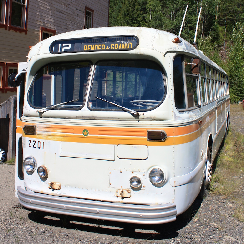 a white bus with yellow trim is parked