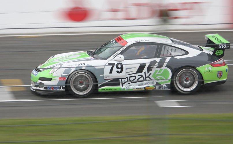 a green and white sports car driving down a race track