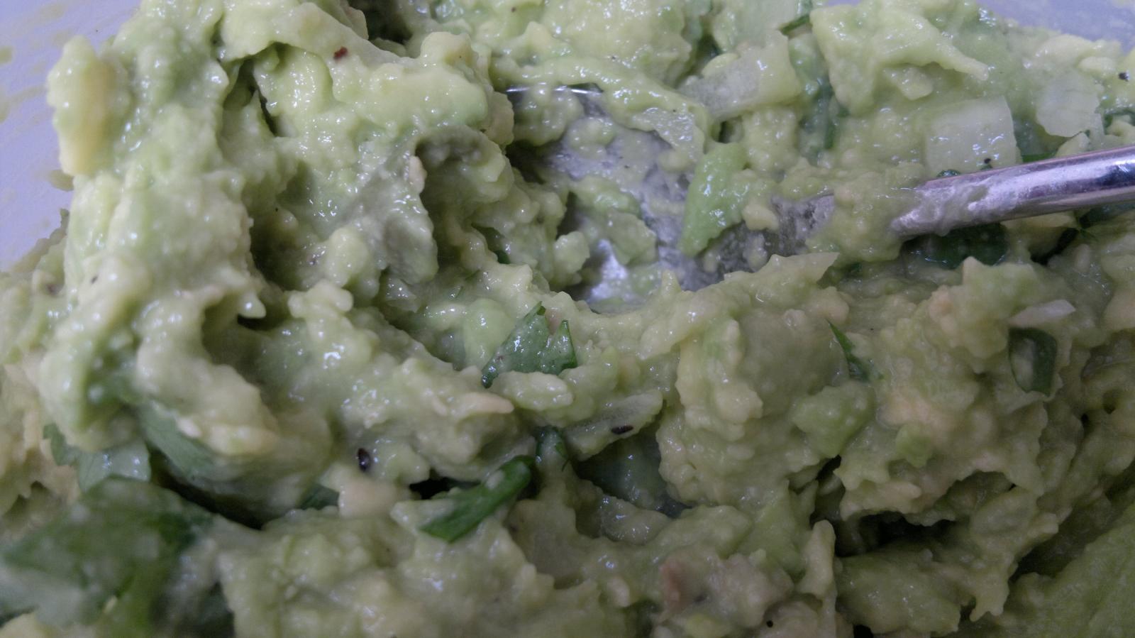 a bowl full of green salsa with a spoon
