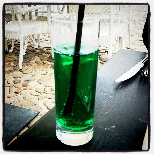 a glass with a green beverage sitting on top of a table