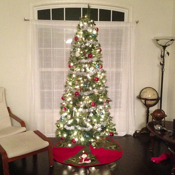 the holiday tree is decorated with ornaments in the corner