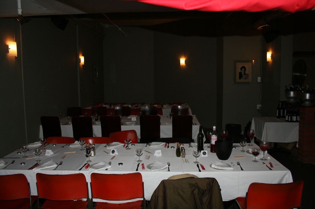 a dining table with many red chairs next to white tablecloths