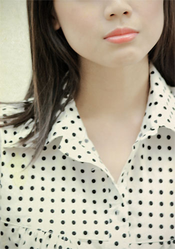 woman with black polka dots shirt looking directly ahead