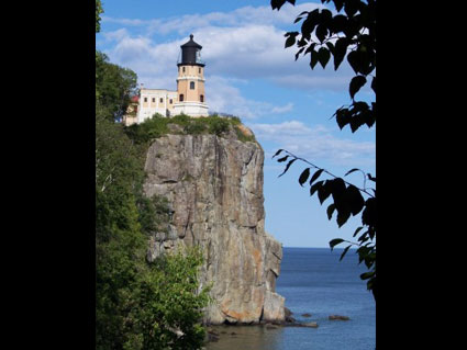 the light house on top of the rock is next to the water