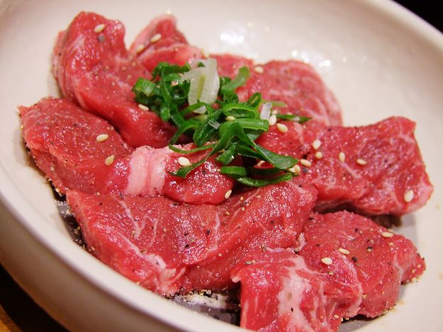 a white plate with raw meat and herbs