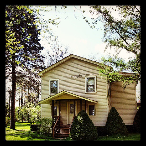 a three story home with many trees in the yard