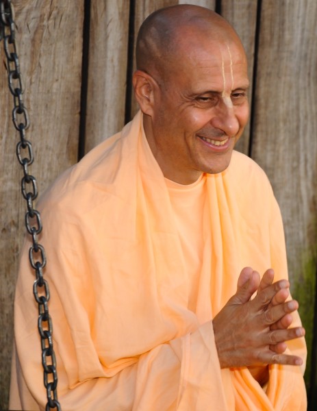 a smiling monk is sitting in front of a wooden fence