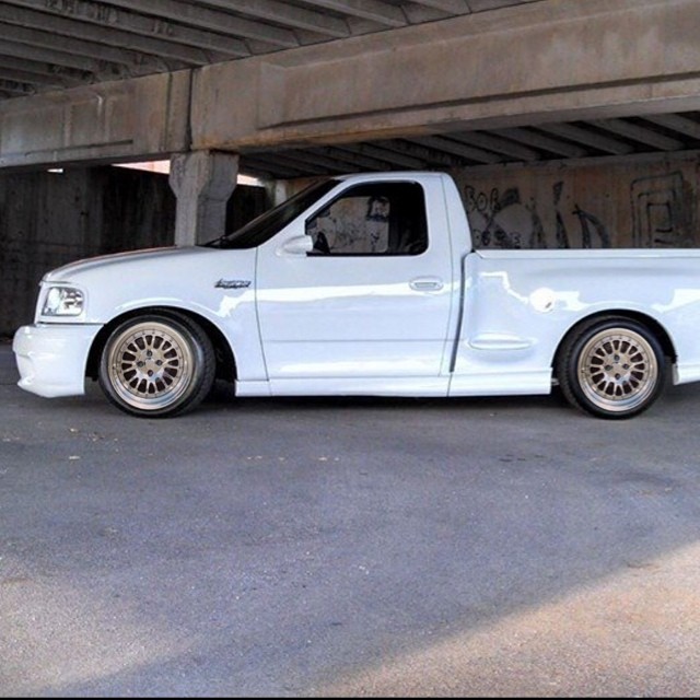 a white pick up truck parked under a bridge