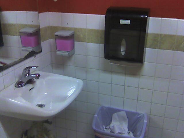 a white bathroom with black and pink towels hanging on a wall