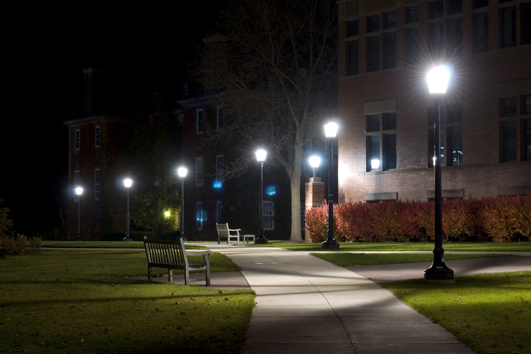 a bench sits on the sidewalk by a light
