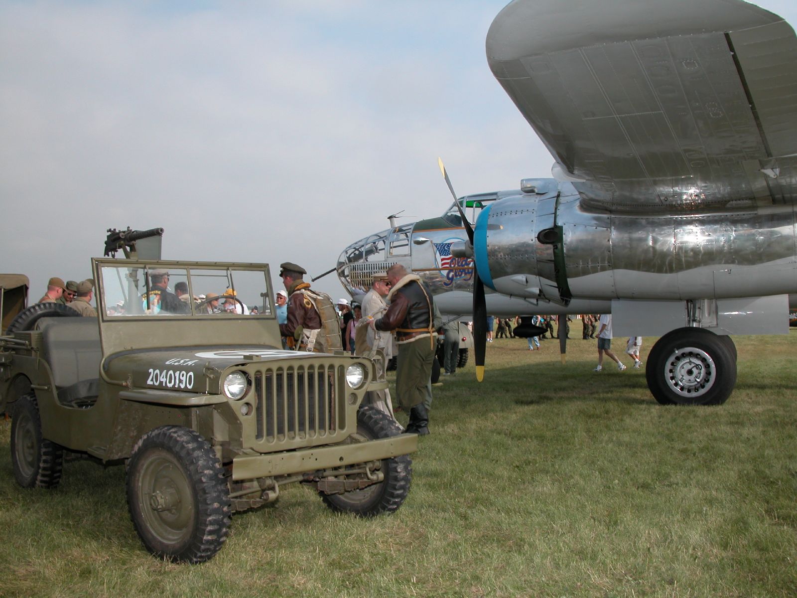 an old jeep with a military jet parked on the ground