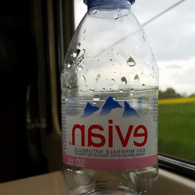 this is a bottle of water sitting on a window ledge