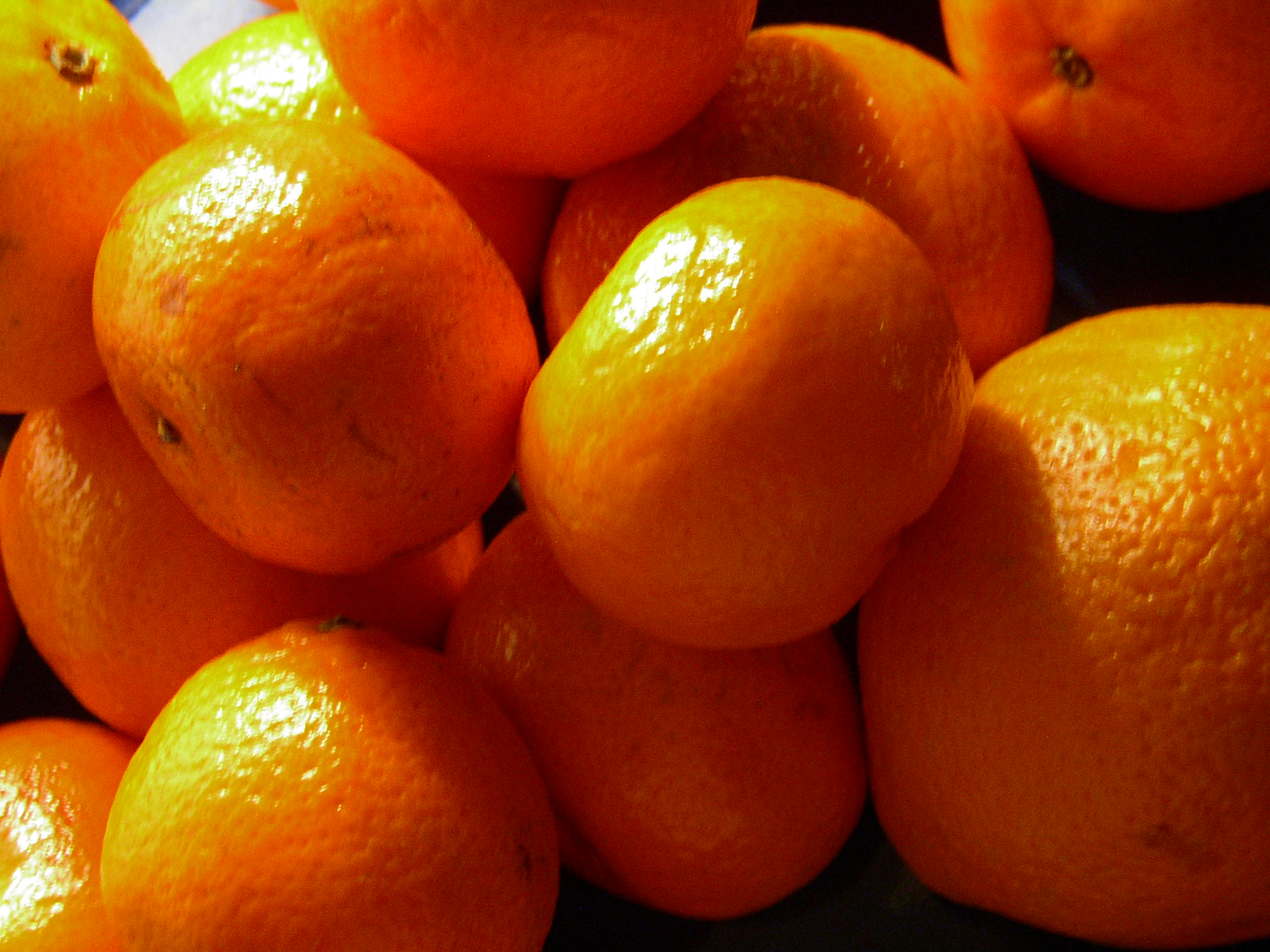 an orange is sitting atop the pile of other citrus fruits