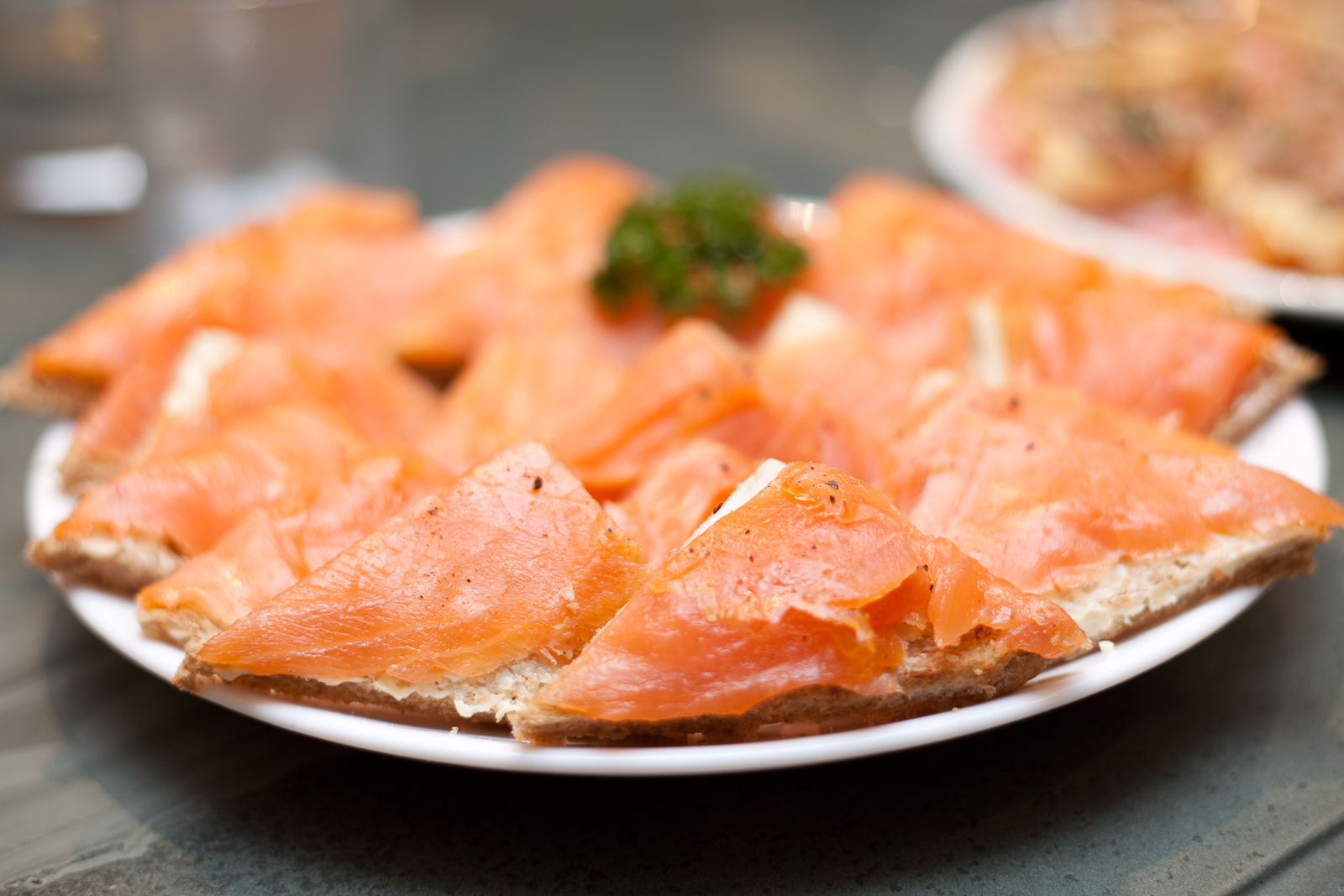 sliced salmon on a plate with garlic sprouts and sauce