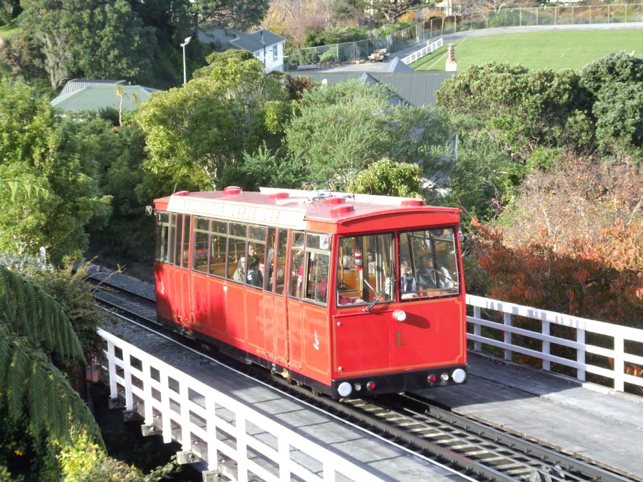 a trolley traveling on a road surrounded by trees