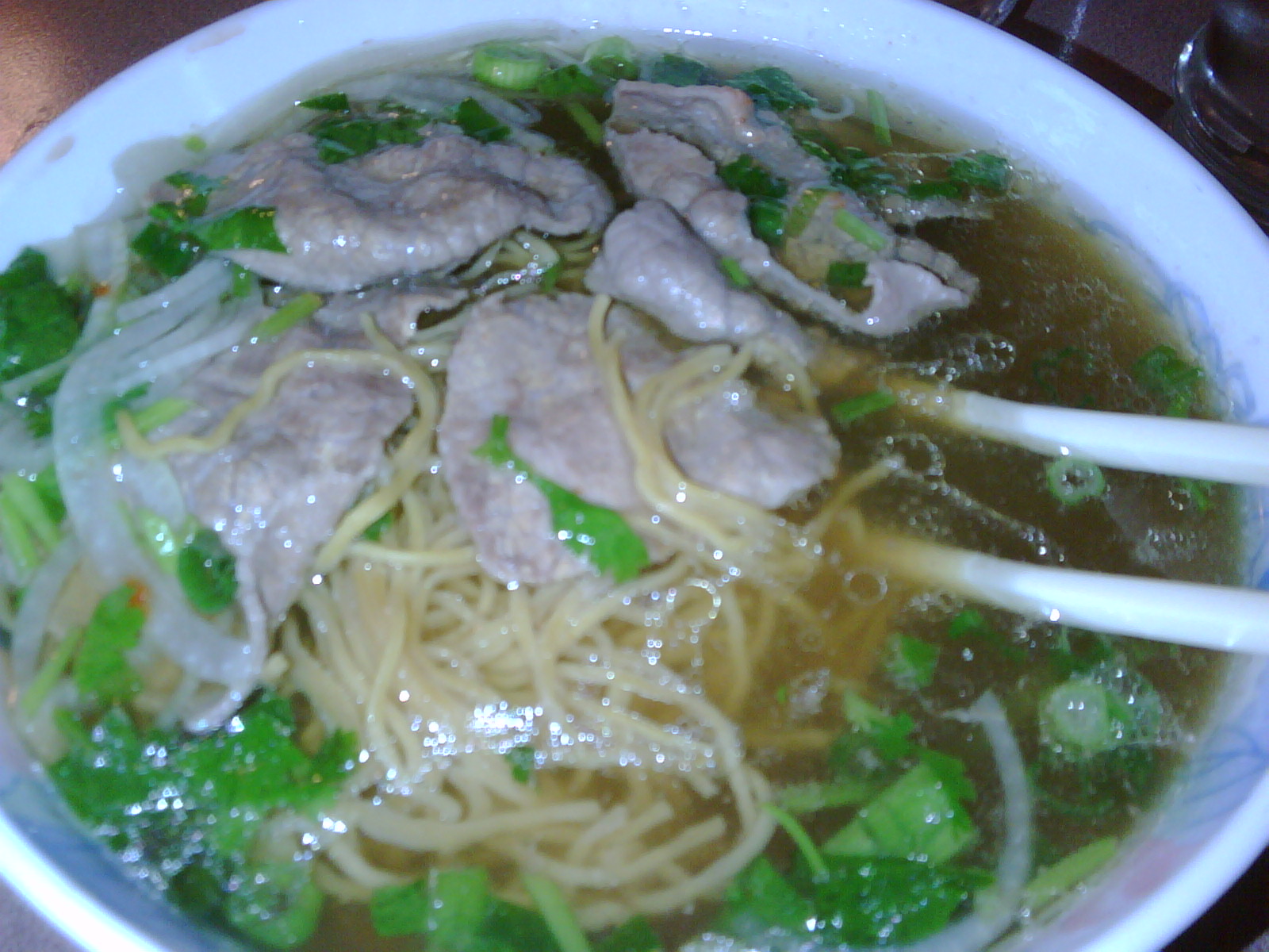 a bowl of meat noodle soup with broccoli