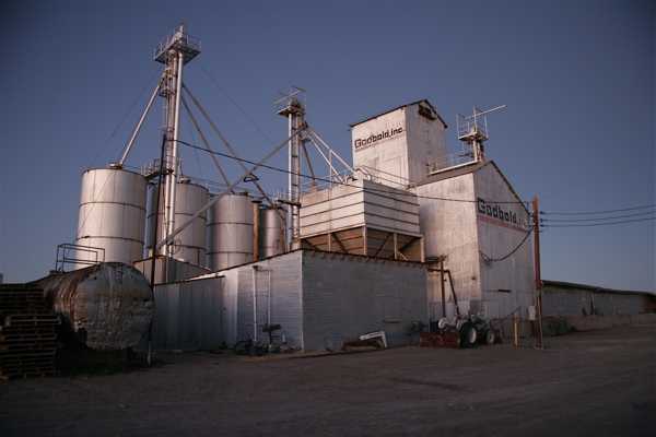 some industrial silos sitting side by side on a cement ground