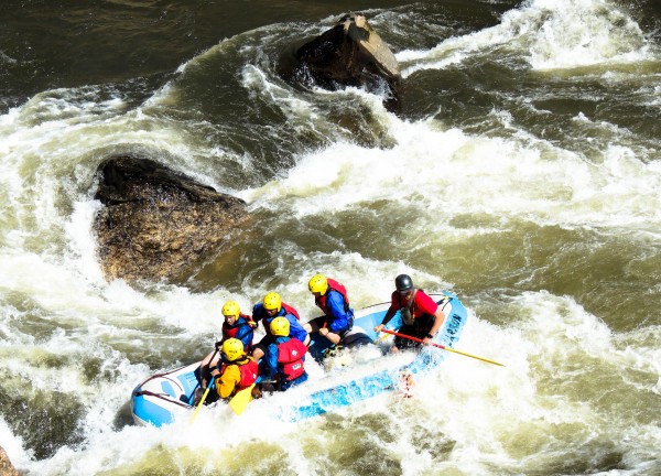 people riding on the back of a raft through rapids