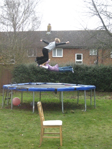 the boy is jumping over the trampoline in the yard