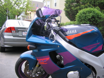 a blue motorcycle parked in front of a gray car