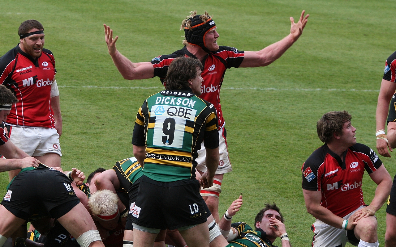 a group of men in red and black jerseys play rugby