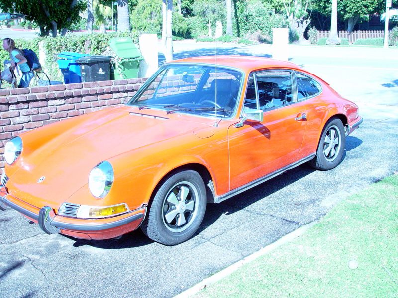 an orange car is parked in front of a brick wall