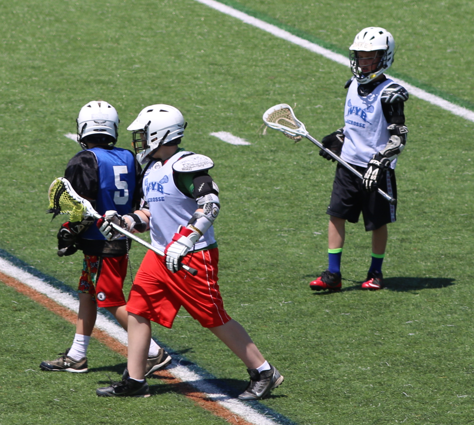 three children are playing lacrosse on the field