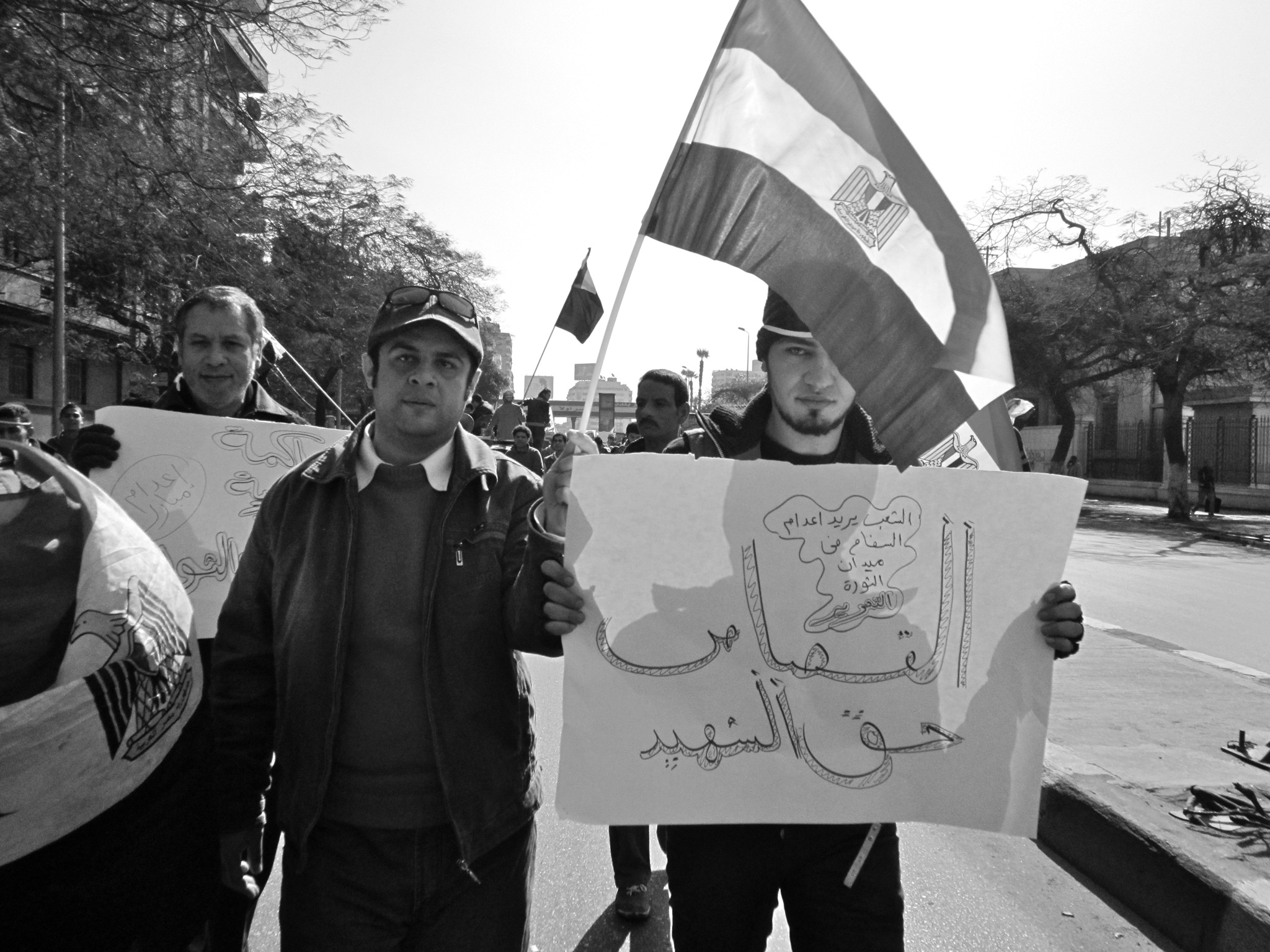 men hold up signs and flags in a protest