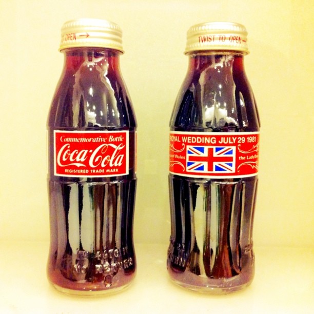 two bottles with black coke sitting on top of a table