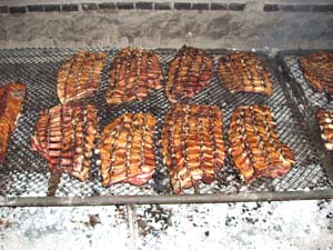 a bunch of bbq food cooking on a grill