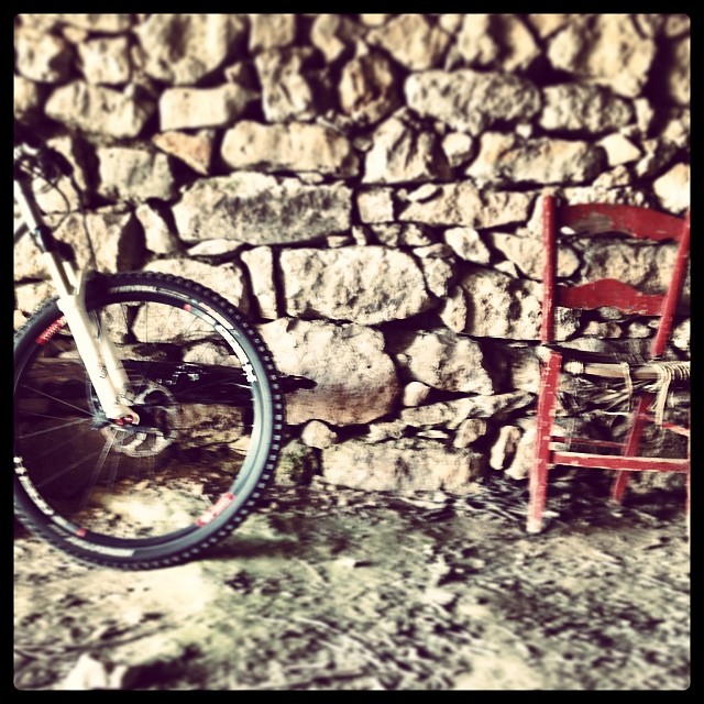 a bike parked next to a red chair and stone wall