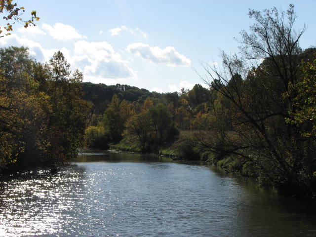 a wide river has trees surrounding it in fall