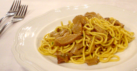 noodles and meat are sitting on a plate next to a fork