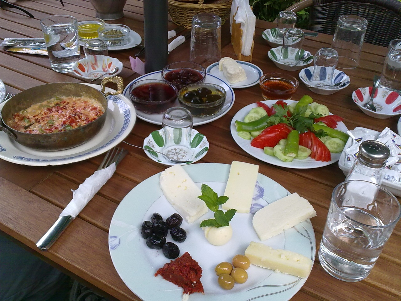 various cheese, fruit and meats are on the plates