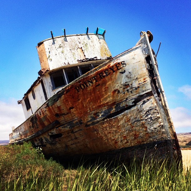 an old boat sitting in some green grass